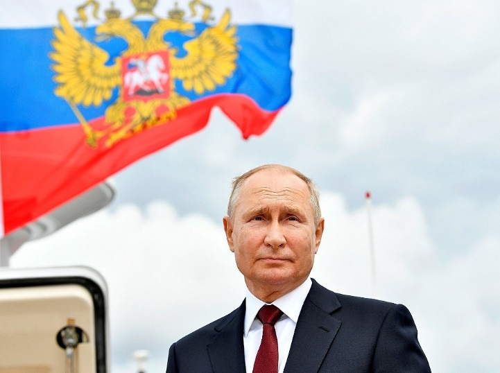 Putin under the Russian flag with the double-headed eagle, the Great Russian symbol of Tsarist Russia.