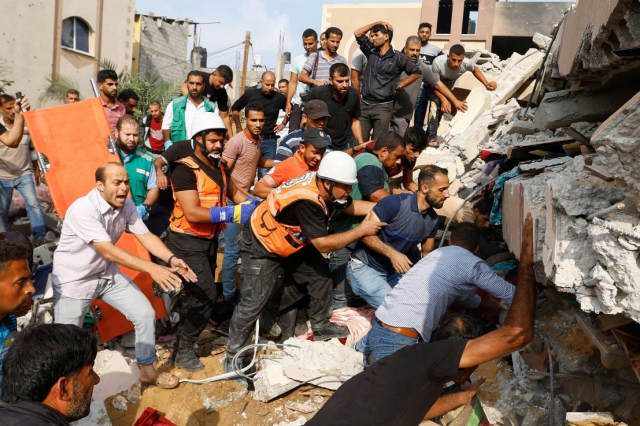 Palestinos buscan personas atrapadas tras un bombardeo israelí a un edificio de viviendas. Gaza, el 8 de octubre de 2023.